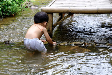 The boy playing in the river trying to make a little stone dam