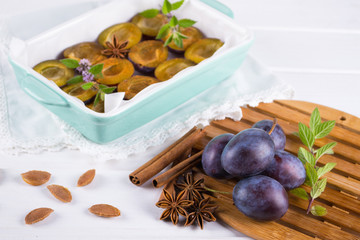 Healthy homemade dessert. Sliced red plums ready for cooking in a baking dish with fresh mint, cinnamon, anise 