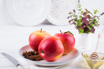 Fresh, ripe organic  sweet apple in dish with cinnamon sticks, anise stars and honey on a white kitchen table. 