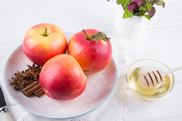 Fresh, ripe organic  sweet apple in dish with cinnamon sticks, anise stars and honey on a white kitchen table. Top view 