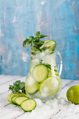 Infused water with cucumber, lime and mint on wooden table