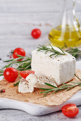 Fresh feta cheese with rosemary on white wooden serving board