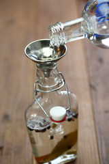making homemade gin, pouring vodka