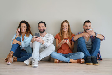 Group of friends using smartphone, sitted on floor