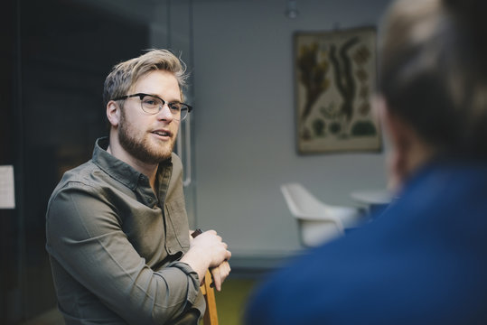 Confident male computer programmer talking to female colleague in office