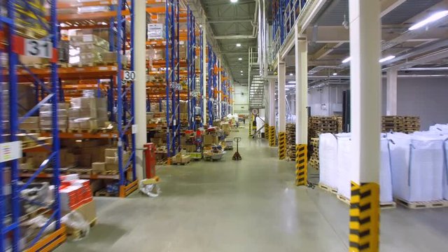Storage, warehouse indoors. Camera goes along shelfs, racks. 4K.
