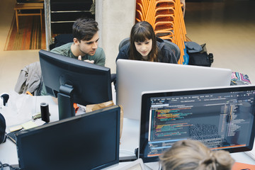 High angle view of computer programmers using desktop PC at office desk