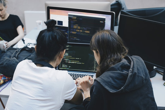 Over the shoulder view of computer programmers using laptop at office desk