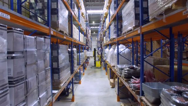 Forklift in a warehouse. Modern forklift unloading racks, shelves in storehouse. Aerial.