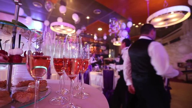 The waiter pours champagne in wineglass, in a restaurant, The waiter pours champagne in crystal glasses, Restaurant interior, buffet table, Waiter in white gloves, close-up