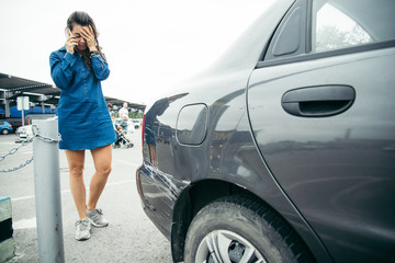 sad woman standing near car with scratch