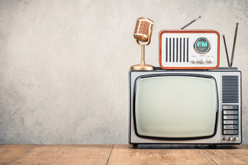 Retro old TV set, FM radio receiver and golden microphone front concrete wall background. Broadcasting concept. Vintage instagram style filtered photo