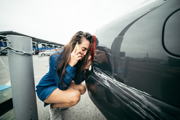 sad woman standing near car with scratch