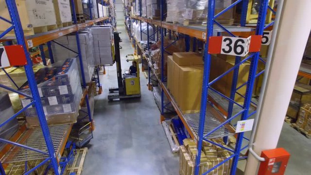 Forklift inside huge industrial warehouse. Aerial shot.