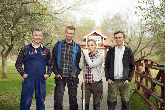 Portrait of confident farmer standing with family on footpath