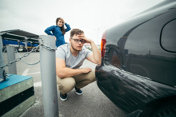sad man looking on car scratch, woman stand behind him