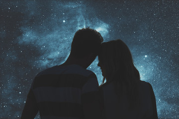 Silhouettes of a young couple under the starry sky.  - obrazy, fototapety, plakaty