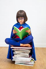 wise schoolgirl with super hero costume reading for girl power