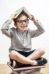 happy schoolboy with missing tooth covering his head with book