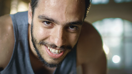 Exhausted Bend Muscular Man Looks into Camera and Rests After Intensive Workout. He's In a Gym and...