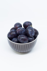 Plums in a bowl, separated, close up. White background.