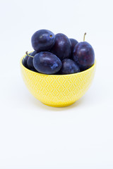 Plums in a bowl, separated, close up. White background.