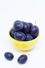 Plums in a bowl, separated, close up. White background.