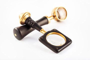Closeup image of two vintage magnifying glasses with wooden handles isolated at white background.