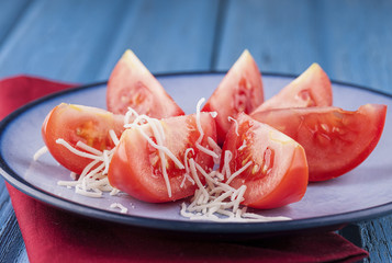 Shredded cheese on tomato wedges.