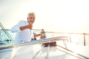 Mature man winding a winch on his sailboat
