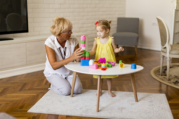 Grandmother playing with little granddaughter in the room