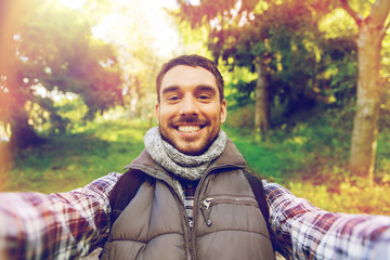 happy man with backpack taking selfie and hiking