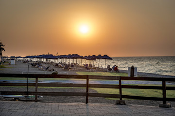 Fototapeta na wymiar a deserted beach with sun umbrellas at sunset on the island of Rhodes