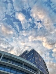 Fototapeta na wymiar белый облака медленно плывут по вечернему небу над синим высоким зданием
