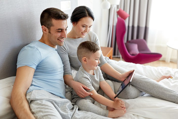 happy family with tablet pc in bed at home