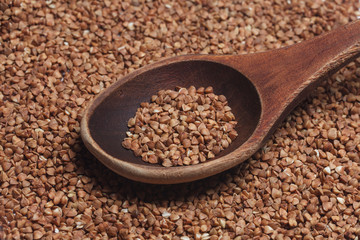 Wooden spoon with buckwheat on the background of buckwhea