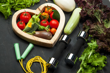 Fresh vegetables, diet and sport on a black wooden background