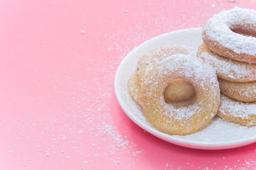 Fried Donuts on pink background with Powdered sugar icing