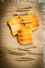 Toasts and wheat on a white wooden background