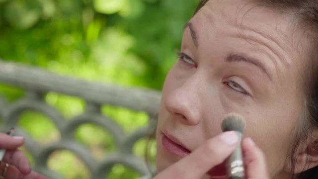 Make up artist applies eyeliner to top of lashlines before photoshoot. Slow motion