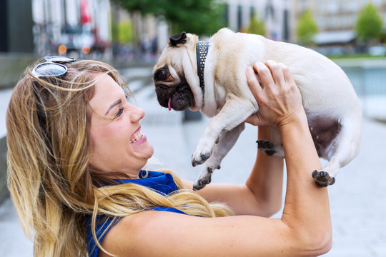 young woman raises up her cute pug