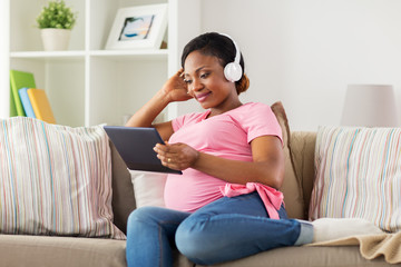Fototapeta premium pregnant woman in headphones with tablet pc