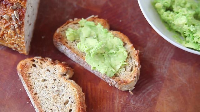 Spreading mashed avocado on slices of toast