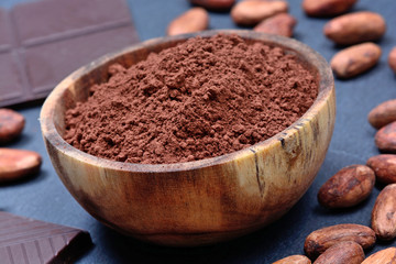 Bowl with cacao powder and chocolate on slate