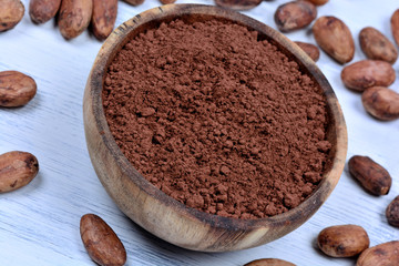 Bowl with cacao powder and beans on table