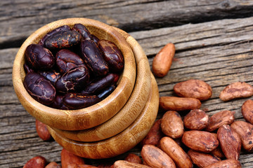 Cocoa beans in a bamboo bowl on wooden table