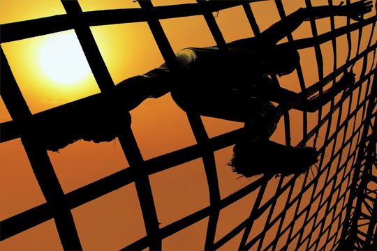 Man climbing a net during sunset. Spartan and gladiator race concept.