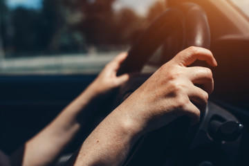 Female hands on car steering wheel