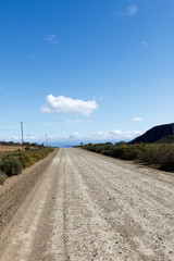 The dusty road with bushes and clouds