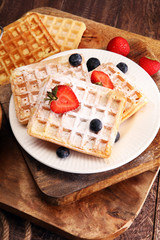 Homemade waffles with berries in plate on wooden table